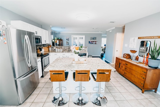 1433 Sun Breeze Dr, Little Elm, TX 75068 - kitchen with appliances with stainless steel finishes, a peninsula, white cabinetry, light stone counters, and a kitchen island