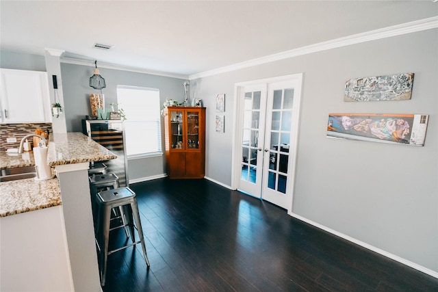 1433 Sun Breeze Dr, Little Elm, TX 75068 - kitchen with french doors, a sink, white cabinetry, a breakfast bar area, and light stone countertops
