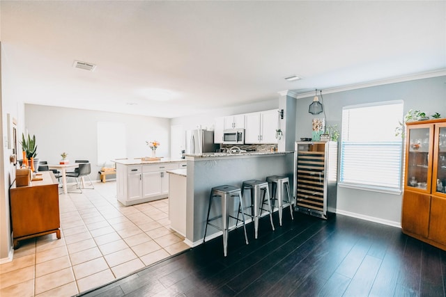 1433 Sun Breeze Dr, Little Elm, TX 75068 - kitchen with appliances with stainless steel finishes, wine cooler, a peninsula, a kitchen breakfast bar, and white cabinetry