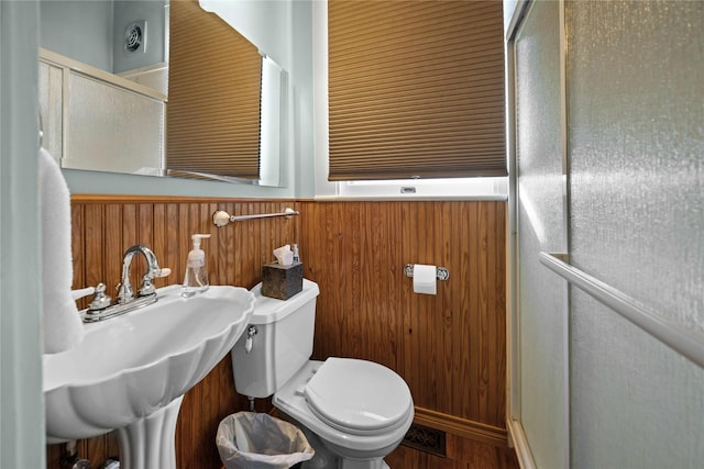 403 S Royall, Palestine, TX 75801 - bathroom featuring toilet, a wainscoted wall, a shower with door, wood walls, and a sink