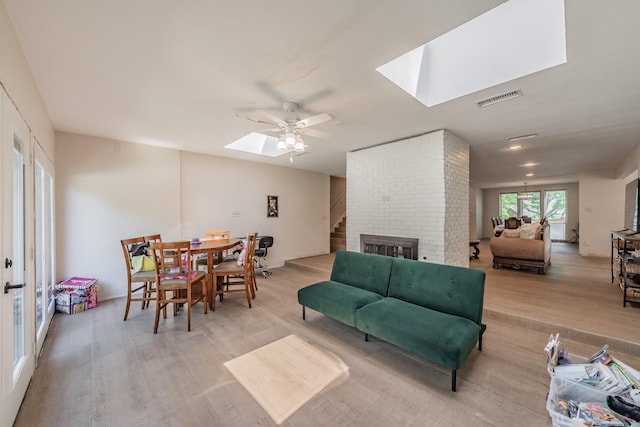 707 Kyle Dr, Arlington, TX 76011 - living area featuring a skylight, light wood finished floors, a ceiling fan, and a fireplace
