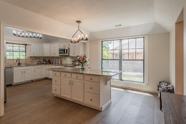 707 Kyle Dr, Arlington, TX 76011 - kitchen with stainless steel appliances, vaulted ceiling, white cabinets, backsplash, and a chandelier