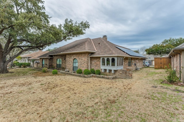 10014 Silver Creek Rd, Dallas, TX 75243 - back of property with brick siding, roof mounted solar panels, a chimney, and a shingled roof