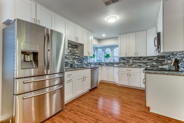 10014 Silver Creek Rd, Dallas, TX 75243 - kitchen featuring stainless steel appliances, light wood-style floors, backsplash, white cabinets, and stone counters