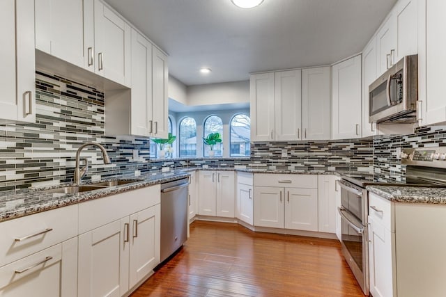 10014 Silver Creek Rd, Dallas, TX 75243 - kitchen featuring stainless steel appliances, a sink, decorative backsplash, light wood-type flooring, and light stone counters