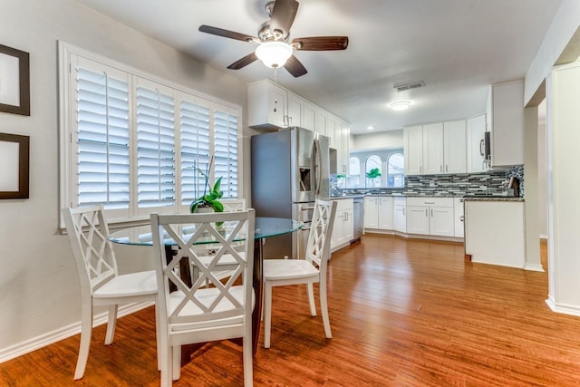 10014 Silver Creek Rd, Dallas, TX 75243 - kitchen with appliances with stainless steel finishes, wood finished floors, tasteful backsplash, and white cabinetry