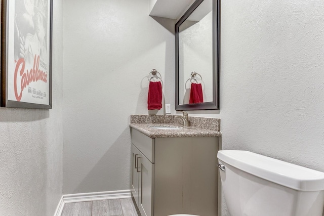 10014 Silver Creek Rd, Dallas, TX 75243 - bathroom featuring wood finished floors, vanity, toilet, baseboards, and a textured wall