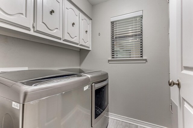 10014 Silver Creek Rd, Dallas, TX 75243 - clothes washing area with washing machine and clothes dryer, cabinet space, and baseboards