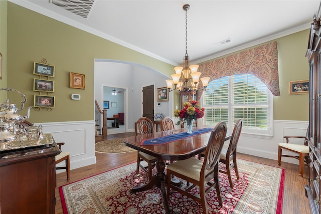 8803 Kelvington Dr, Frisco, TX 75035 - dining space featuring a chandelier, arched walkways, wainscoting, crown molding, and wood finished floors