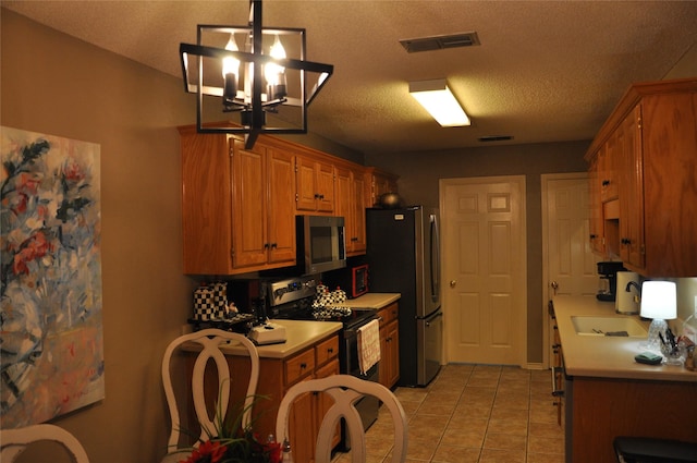 1720 Red Oak Cir, Sulphur Springs, TX 75482 - kitchen with light countertops, appliances with stainless steel finishes, light tile patterned floors, brown cabinetry, and a textured ceiling