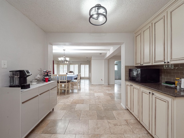4029 Aragon Dr, Fort Worth, TX 76133 - kitchen with black microwave, cream cabinets, a chandelier, backsplash, and a textured ceiling