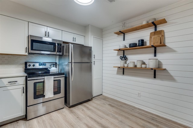 7640 W Greenway Blvd Unit 5P, Dallas, TX 75209 - kitchen featuring stainless steel appliances, open shelves, light wood-style floors, white cabinets, and wood walls