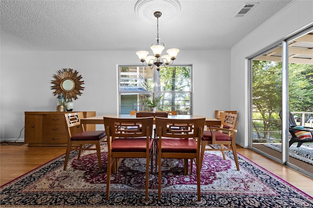 210 Harbor Dr, Gun Barrel City, TX 75156 - dining area with a chandelier, plenty of natural light, light wood finished floors, and a textured ceiling
