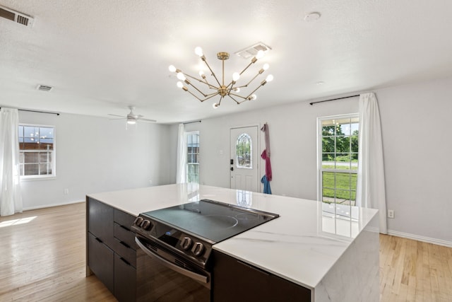 3843 Bernal Dr, Dallas, TX 75212 - kitchen with black electric range, light wood-type flooring, a chandelier, a kitchen island, and baseboards