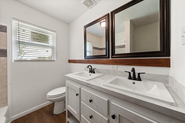 527 Dison Dr, Waco, TX 76706 - bathroom featuring wood finished floors, toilet, double vanity, baseboards, and a bathtub