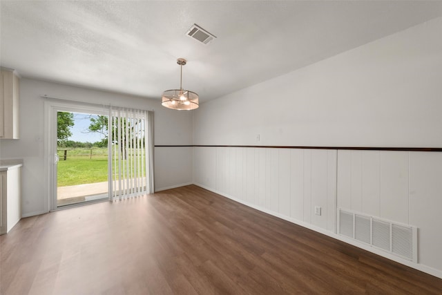 527 Dison Dr, Waco, TX 76706 - unfurnished dining area with a chandelier, wood finished floors, a decorative wall, and wainscoting