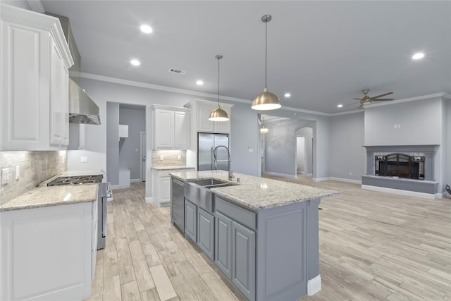 12198 Briargove Ln, Talty, TX 75126 - kitchen featuring stainless steel appliances, ceiling fan, arched walkways, wall chimney exhaust hood, and white cabinets