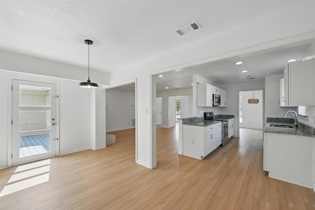 700 Brentwood Ln, Richardson, TX 75080 - kitchen with appliances with stainless steel finishes, a sink, white cabinetry, light wood finished floors, and recessed lighting