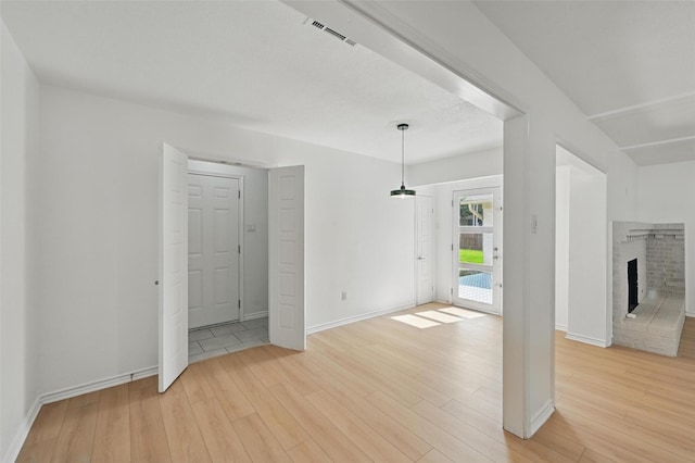 700 Brentwood Ln, Richardson, TX 75080 - empty room with light wood-style flooring, baseboards, and a brick fireplace