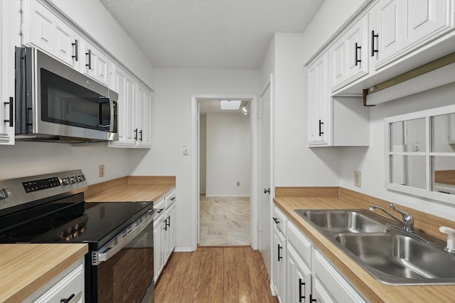 4448 Wind River Ln, Garland, TX 75042 - kitchen with appliances with stainless steel finishes, a sink, white cabinets, wood finished floors, and butcher block counters