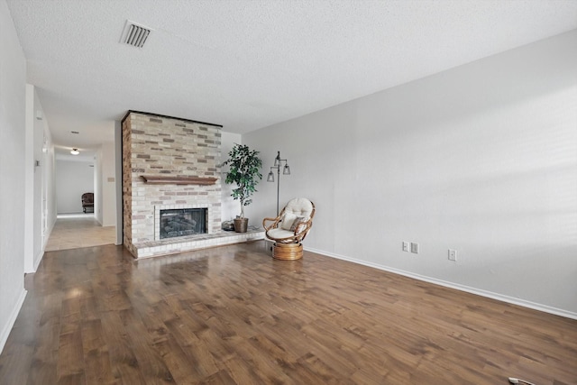 4448 Wind River Ln, Garland, TX 75042 - unfurnished living room with baseboards, wood finished floors, a brick fireplace, and a textured ceiling