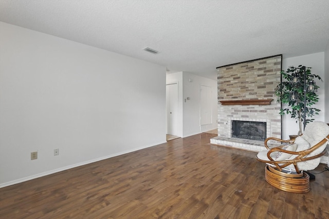 4448 Wind River Ln, Garland, TX 75042 - unfurnished living room featuring wood finished floors, a fireplace, a textured ceiling, and baseboards
