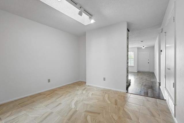 4448 Wind River Ln, Garland, TX 75042 - unfurnished room with a textured ceiling, rail lighting, and baseboards
