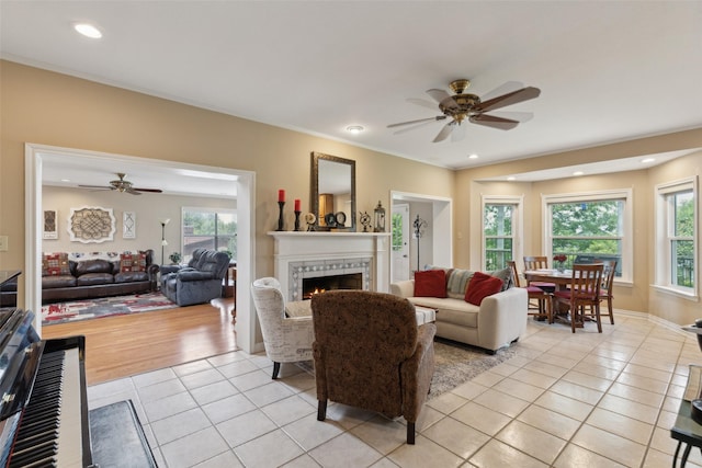 7632 Westwind Dr, Fort Worth, TX 76179 - living area featuring light tile patterned floors, a ceiling fan, a lit fireplace, recessed lighting, and crown molding