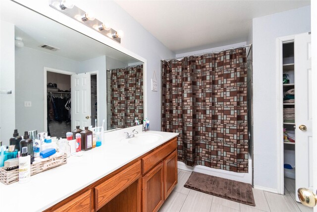 1011 Liffey Dr, Pflugerville, TX 78660 - bathroom featuring a walk in closet, vanity, and a shower with shower curtain