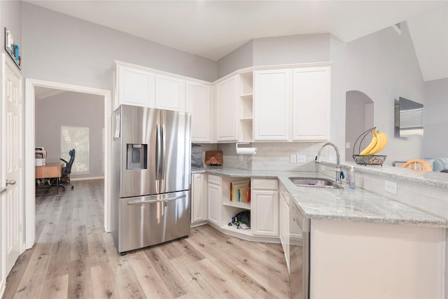 kitchen featuring stainless steel appliances, open shelves, a sink, light wood finished floors, and a peninsula