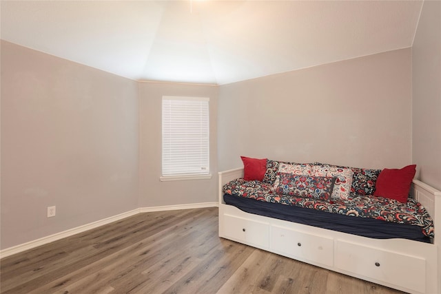 bedroom featuring wood finished floors, lofted ceiling, and baseboards