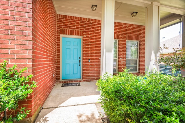 doorway to property with brick siding and a porch