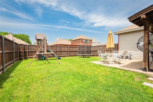 view of yard featuring a trampoline, a playground, and a patio