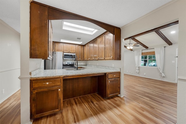 178 Norwood Dr, Woodway, TX 76712 - kitchen featuring appliances with stainless steel finishes, light wood-type flooring, a sink, a skylight, and crown molding