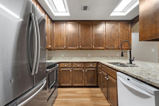 178 Norwood Dr, Woodway, TX 76712 - kitchen featuring stainless steel appliances, a sink, light wood-type flooring, and light stone counters
