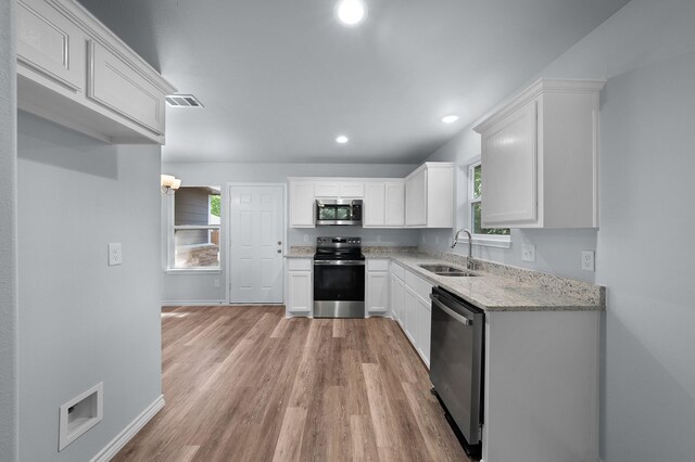 804 Hemlock Dr, West Tawakoni, TX 75474 - kitchen featuring stainless steel appliances, a sink, white cabinets, light wood-type flooring, and recessed lighting