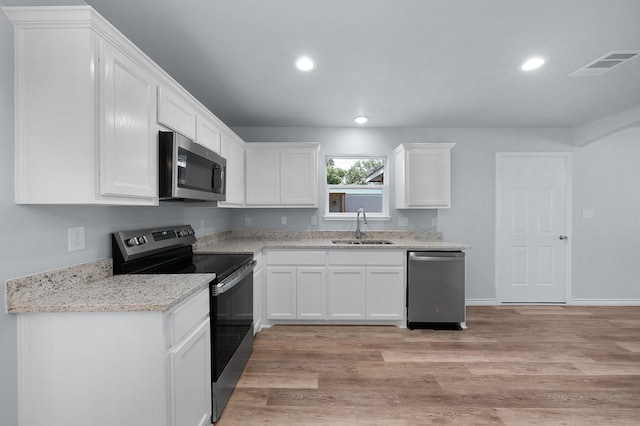 804 Hemlock Dr, West Tawakoni, TX 75474 - kitchen with stainless steel appliances, a sink, light wood-style flooring, recessed lighting, and white cabinets