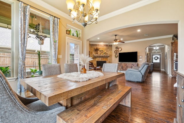 4307 Savannah Ln, Granbury, TX 76049 - dining space featuring arched walkways, a fireplace, dark wood-style flooring, ornamental molding, and a chandelier