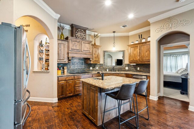 4307 Savannah Ln, Granbury, TX 76049 - kitchen featuring appliances with stainless steel finishes, backsplash, an island with sink, ornamental molding, and dark wood finished floors