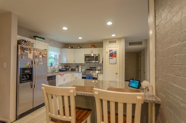 2209 Ridgewood Dr, Sherman, TX 75092 - kitchen with appliances with stainless steel finishes, white cabinets, recessed lighting, a breakfast bar area, and a sink
