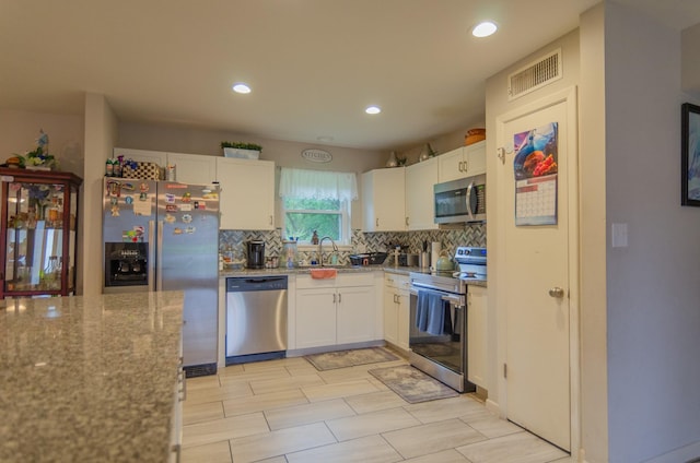 2209 Ridgewood Dr, Sherman, TX 75092 - kitchen featuring stainless steel appliances, tasteful backsplash, white cabinetry, light stone countertops, and recessed lighting