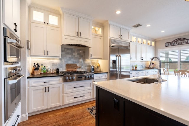 112 Mustang Dr, Fate, TX 75087 - kitchen with stainless steel appliances, a sink, backsplash, white cabinets, and light wood-type flooring