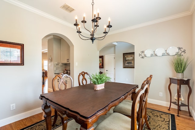 112 Mustang Dr, Fate, TX 75087 - dining area with baseboards, light wood-style floors, ornamental molding, arched walkways, and a chandelier