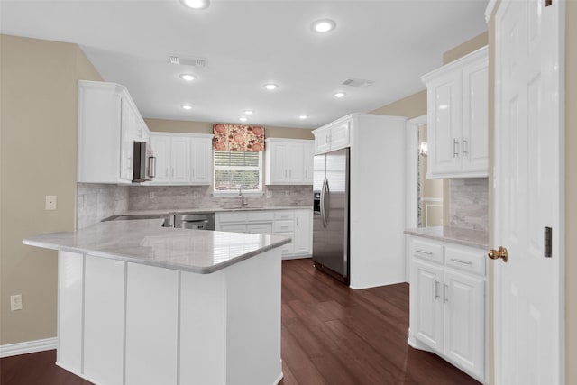2103 Greenbrier St, Denison, TX 75020 - kitchen featuring appliances with stainless steel finishes, a peninsula, dark wood-style floors, a sink, and white cabinets