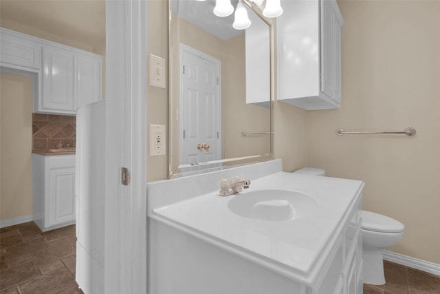 2103 Greenbrier St, Denison, TX 75020 - bathroom with vanity, baseboards, toilet, and tasteful backsplash