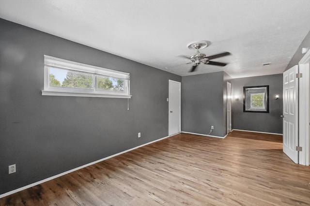 spare room featuring healthy amount of natural light, wood finished floors, ceiling fan, and baseboards