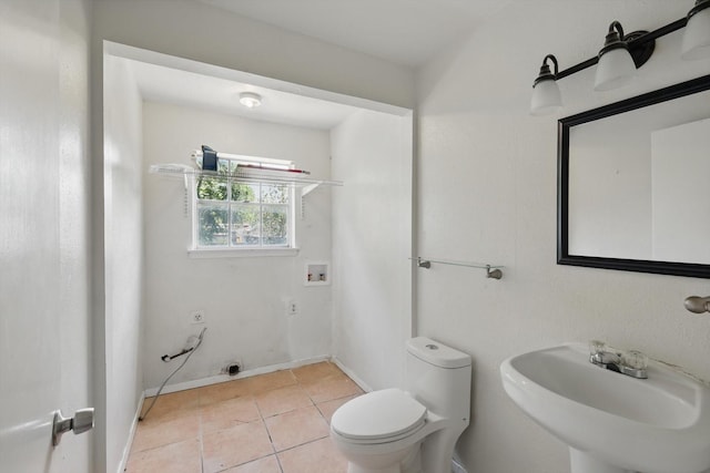half bath featuring a sink, toilet, tile patterned flooring, and baseboards