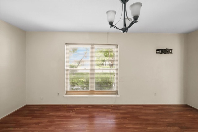 unfurnished room featuring wood finished floors, a chandelier, and baseboards