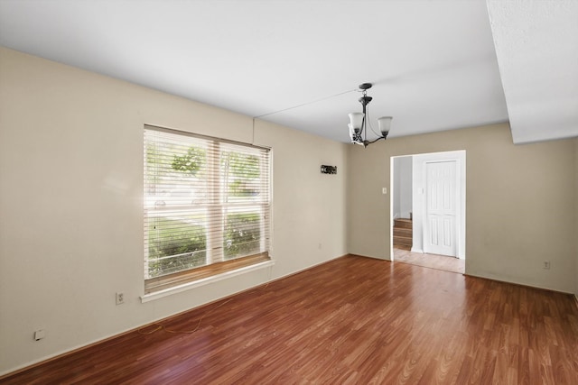 unfurnished room featuring wood finished floors and a chandelier