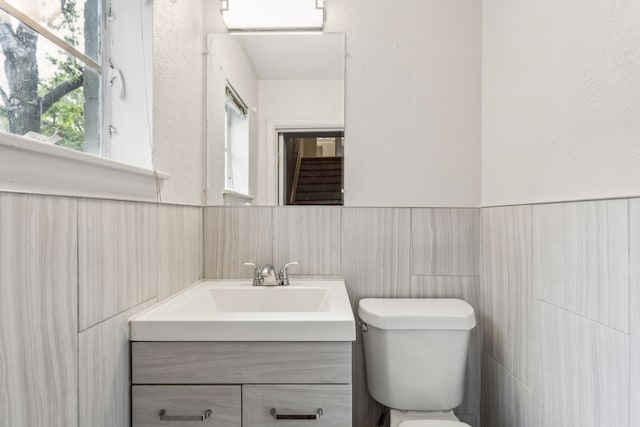 5033 N Hall St, Dallas, TX 75235 - bathroom featuring vanity, toilet, wainscoting, and tile walls